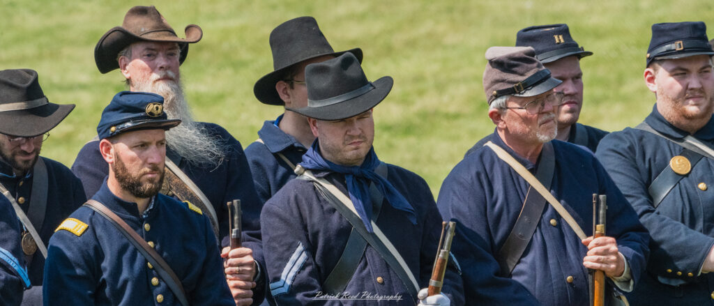 Union soldiers gathered in formation, wearing their distinctive blue uniforms and equipped with rifles. Their posture is disciplined and alert, embodying the camaraderie and determination of the Union Army as they prepare for their next move in the Civil War.